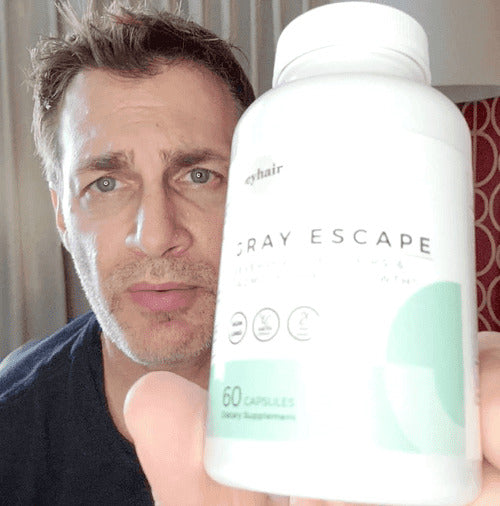A person holding a bottle of 'Gray Escape' hair supplements.